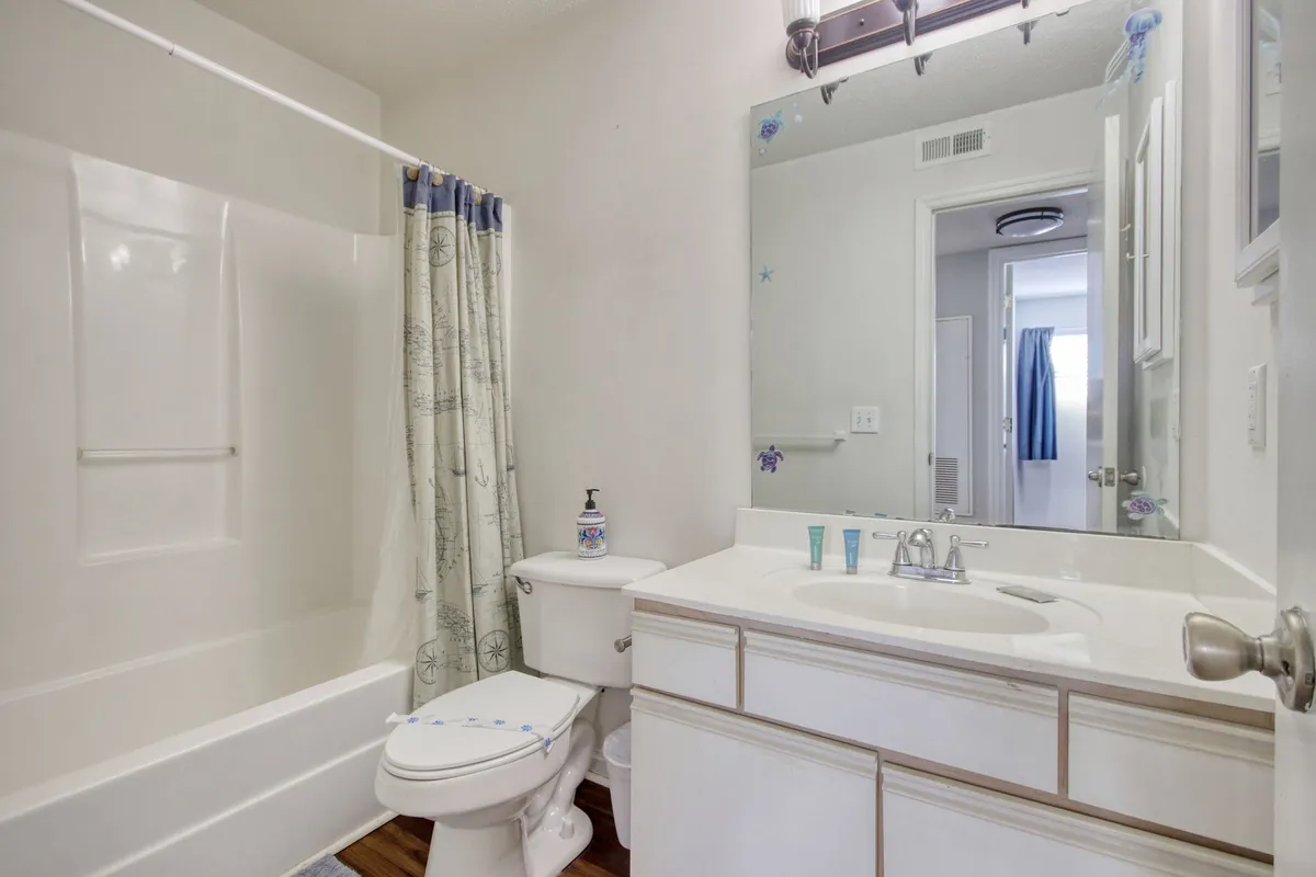 A practical, inviting bathroom with a sink, mirror, and a shower curtain. The space is well-lit and clean, designed for daily routines and relaxation.