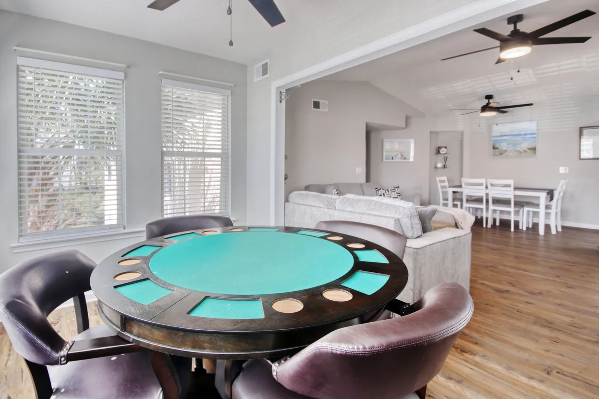 A playful, open space featuring a poker table with comfortable seating that flows seamlessly into the living area. The setup invites group activities like game nights or relaxed hangouts, emphasizing a friendly, sociable vibe.