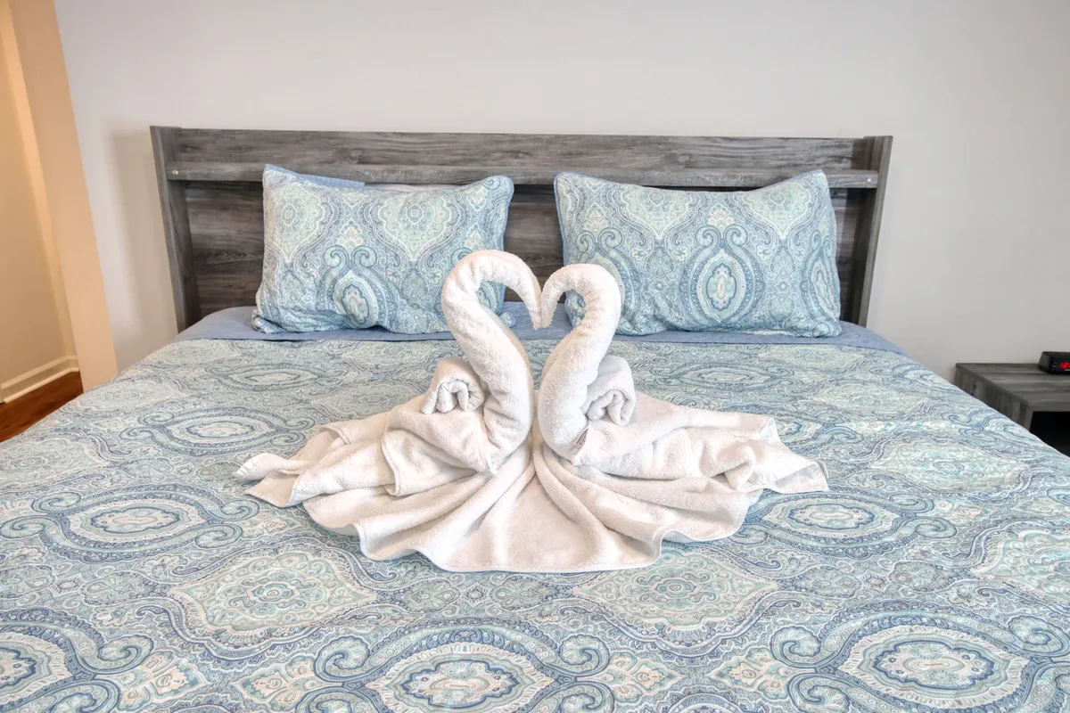 A romantic bedroom scene with carefully arranged towel swans on decorative bedding and a stylish headboard, exuding intimacy and thoughtful touches ideal for couples.
